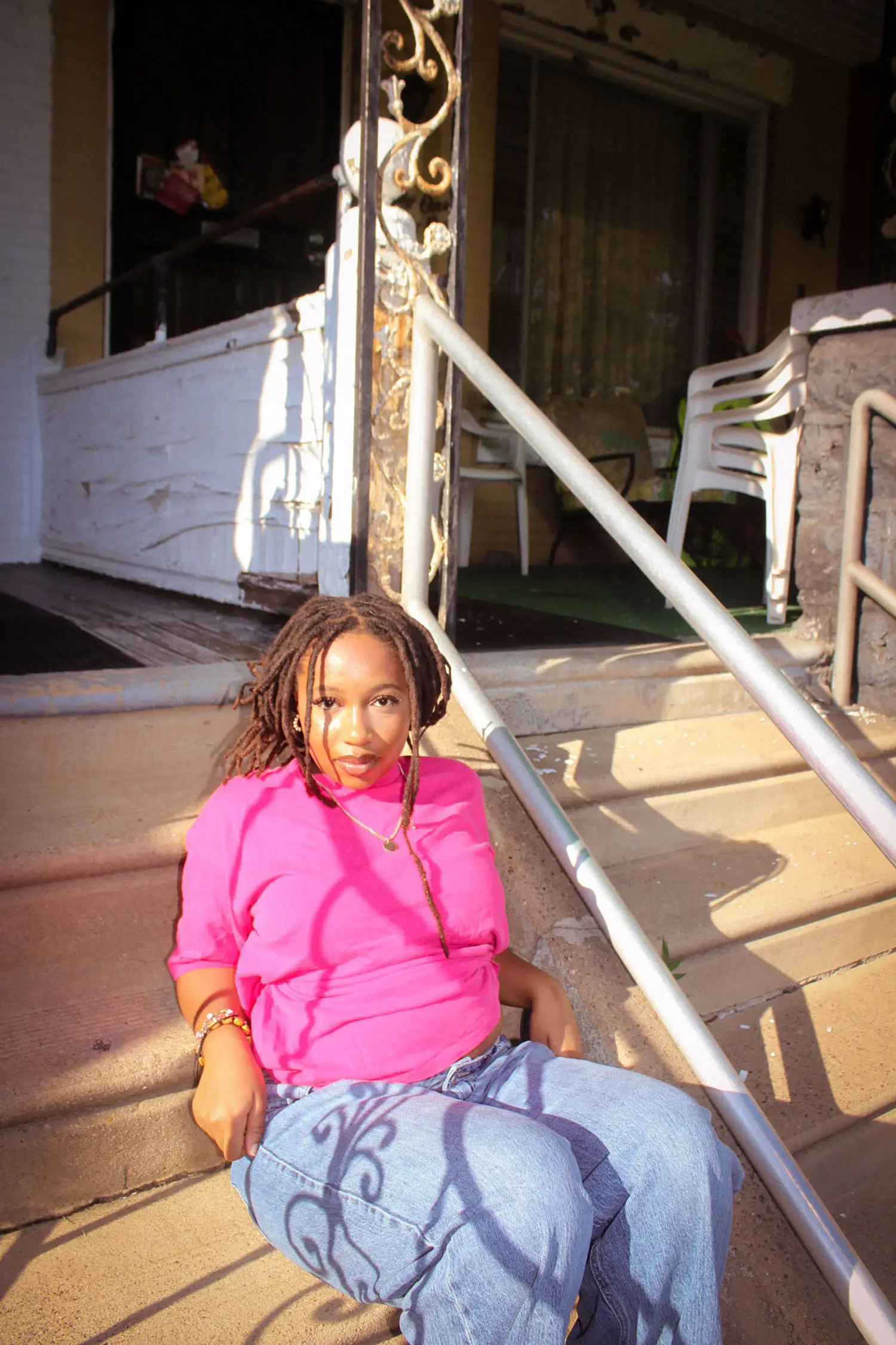 Fatoumata Sidibe sitting on porch steps with chairs behind her.