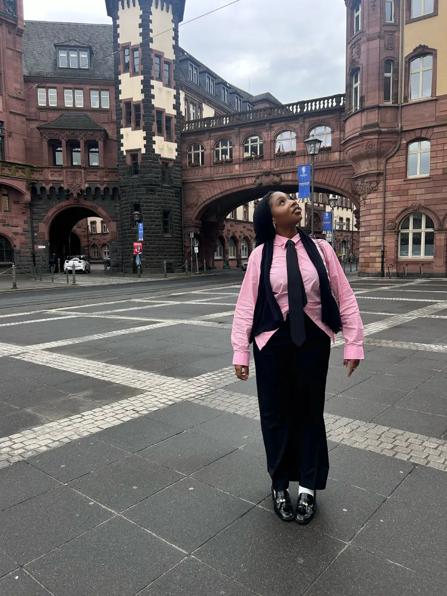 Fatoumata Sidibe looking up at the buildings while standing in the center of a city.