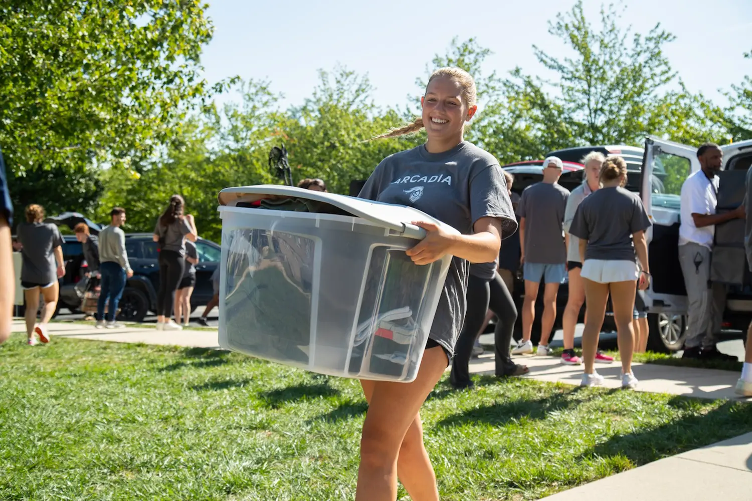 A student athlete carrying a bin of student belongings to their room.