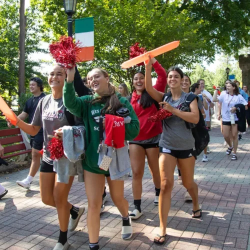 Student athletes walking down the Walk of Pride with pom-poms from Grey Towers