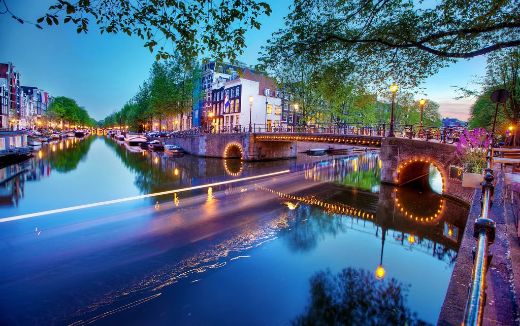 canal in Amsterdam at sunset, lit with boats and rowhomes