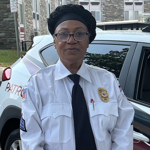 Sergeant Theresa Turner stands by a white and red patrol car for Campus Security.