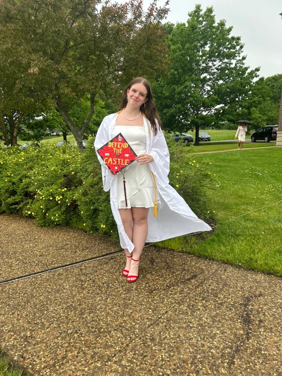 Ella Walsh posing with her graduation cap that reads "Defend the Castle".