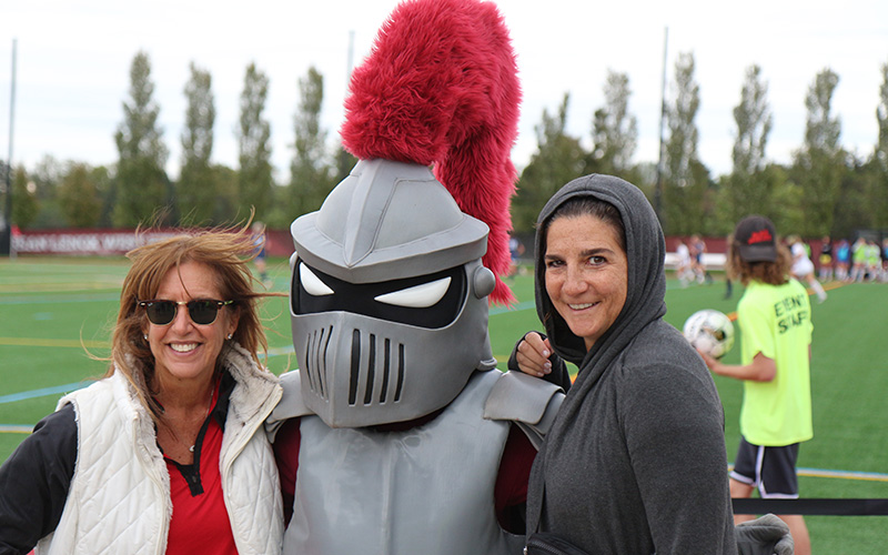 Two people posing with Archie, the mascot, in the middle.