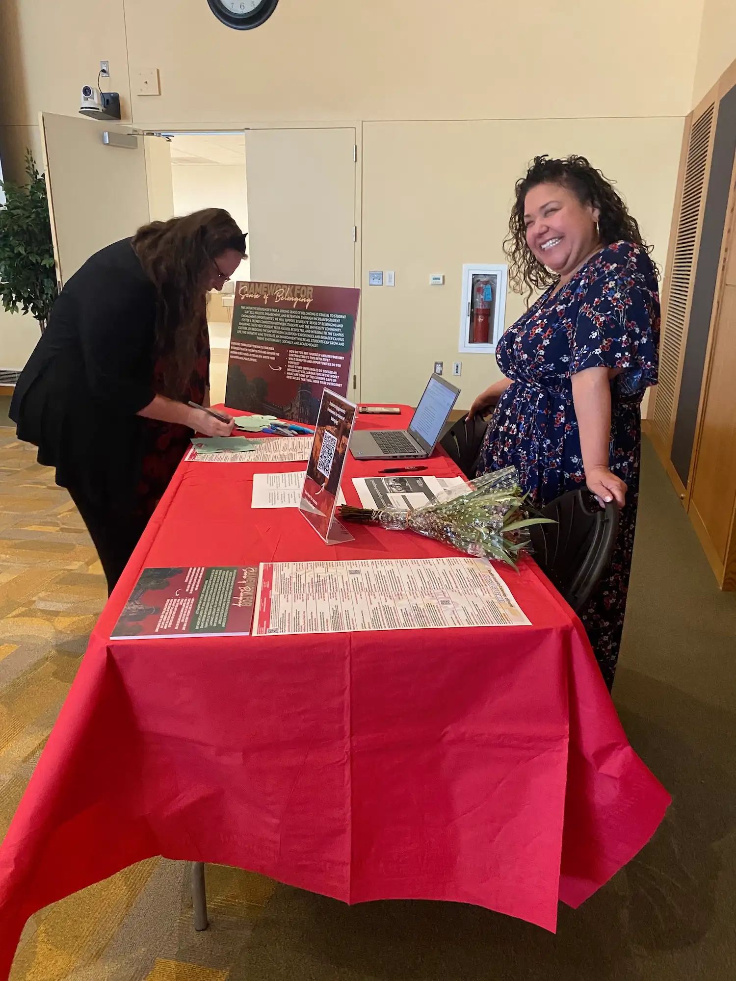 Christine Storch from the Division of Campus Life stands behind a table with a ted table cloth in the Great Room