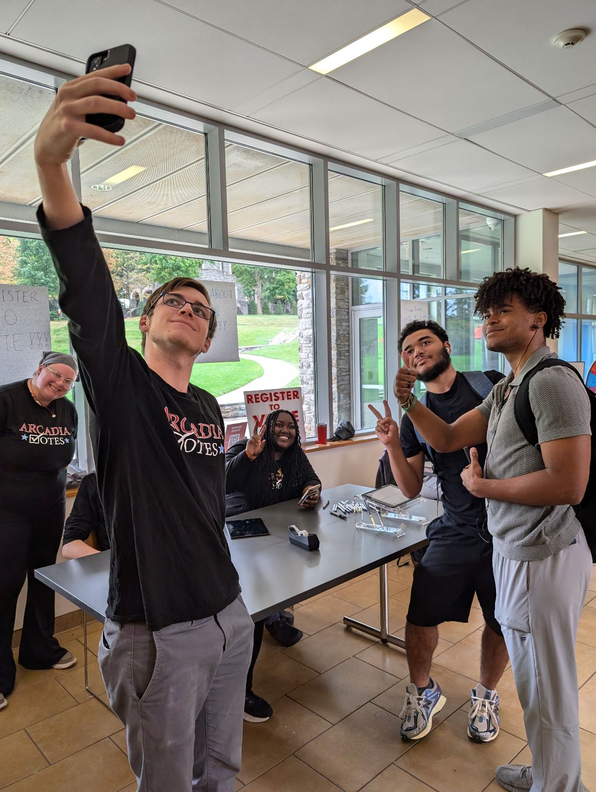 a student wearing an Arcadia Votes t-shirt takes a selfie with others