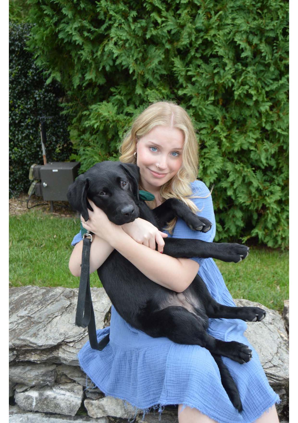 Lily Roberti '28 holding a black lab puppy