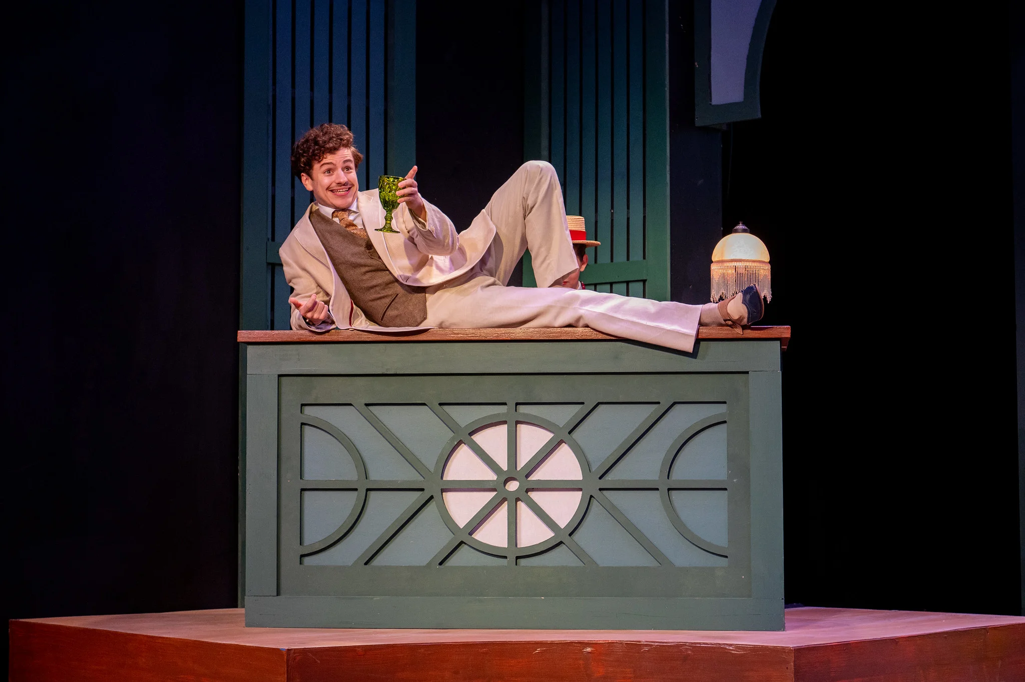 One actor on stage for a play sitting on a bar.