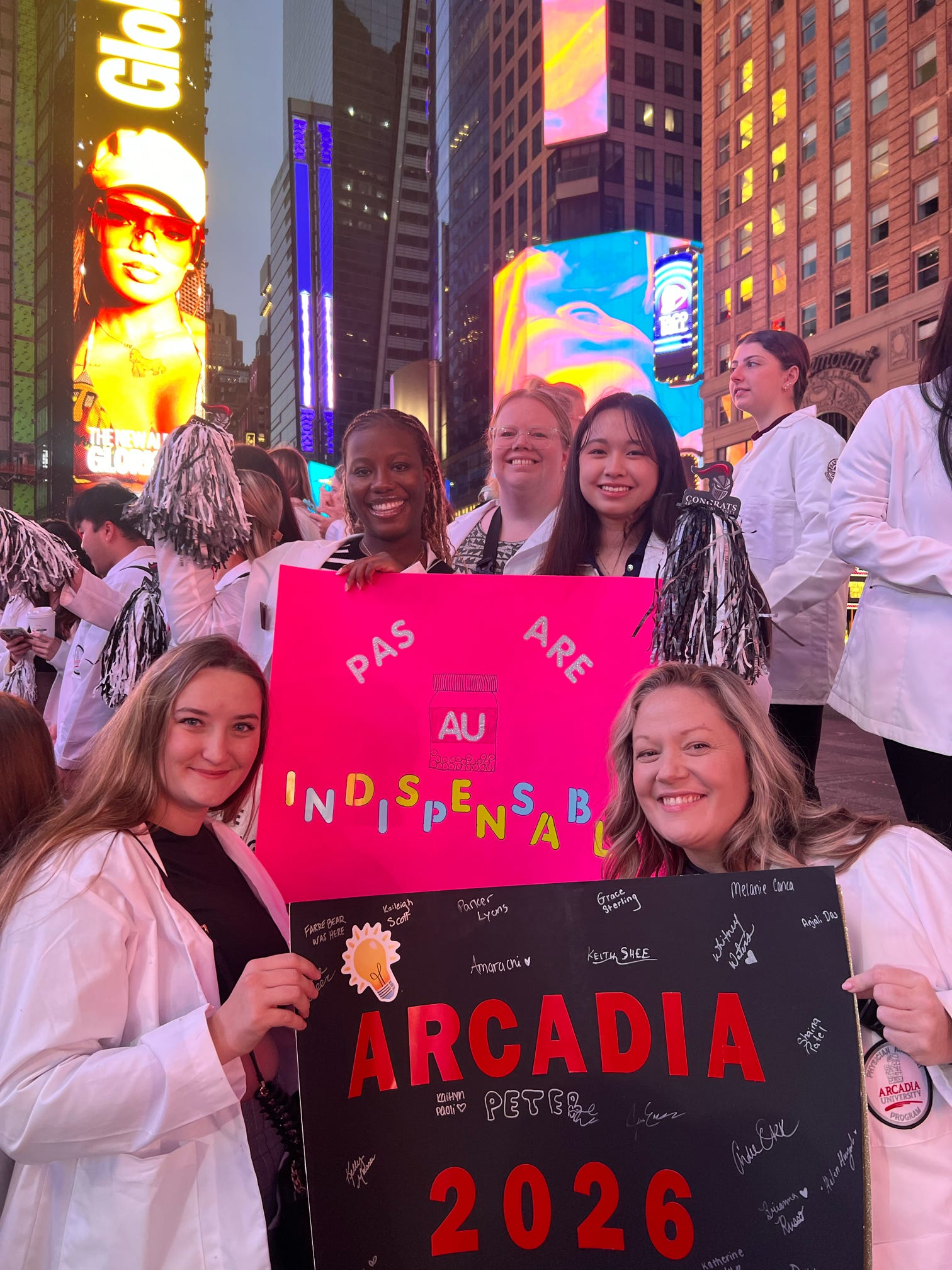 A group of PA students from the Class of 2026 take a selfie holding signs saying "PAs are indispensible" and "Arcadia 2026"