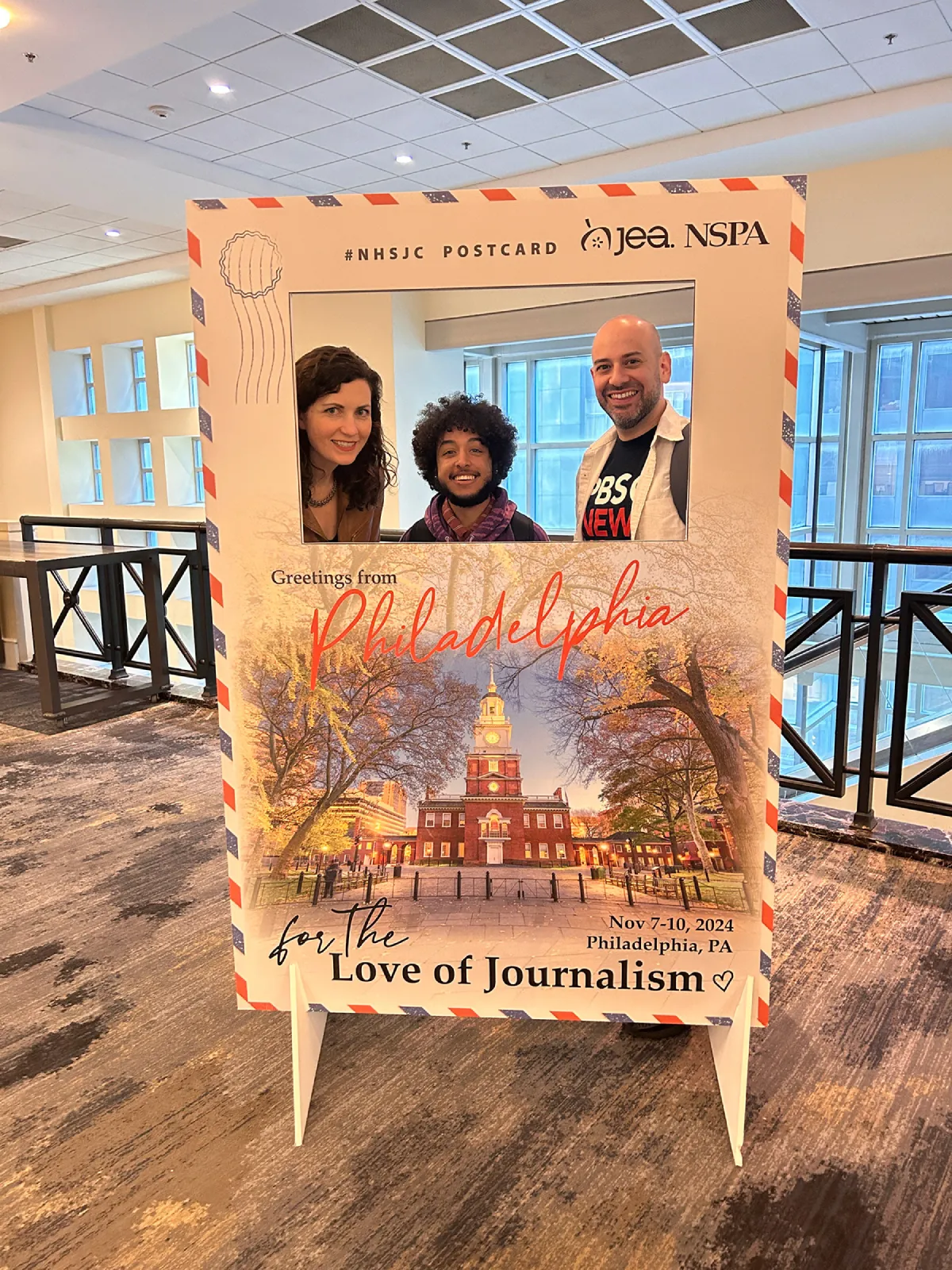 Ethan Rodriguez ’27 and two others posing behind a "Love of Journalism" sign.