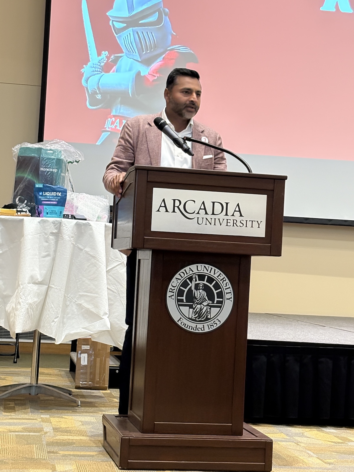 president ajay nair standing at a podium in the great room at the 2nd annual first-generation student celebration