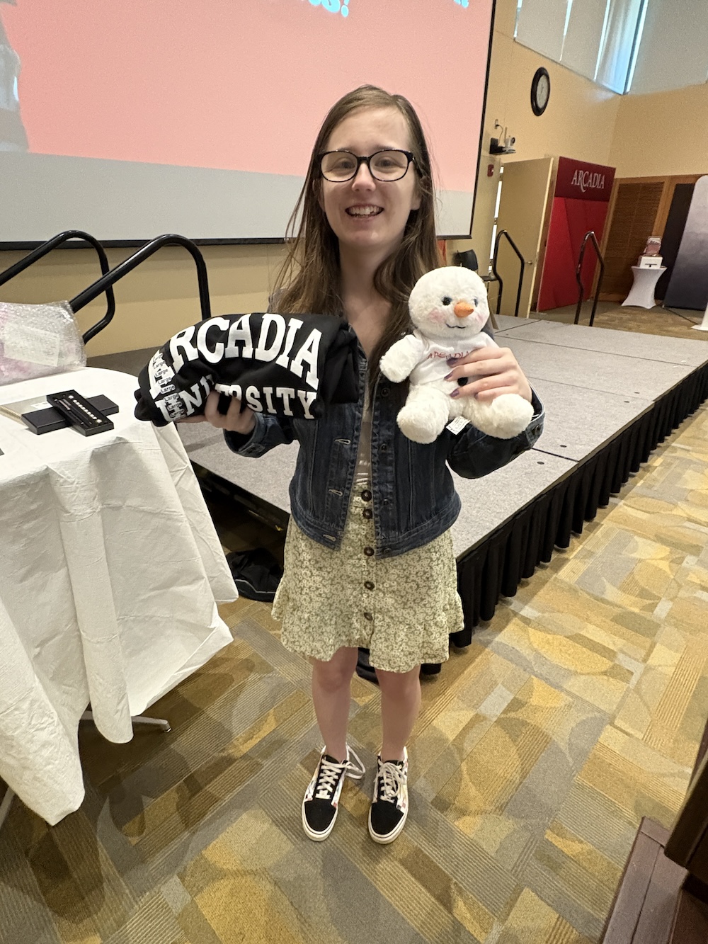 a student holds a stuffed animal and arcadia sweatshirt