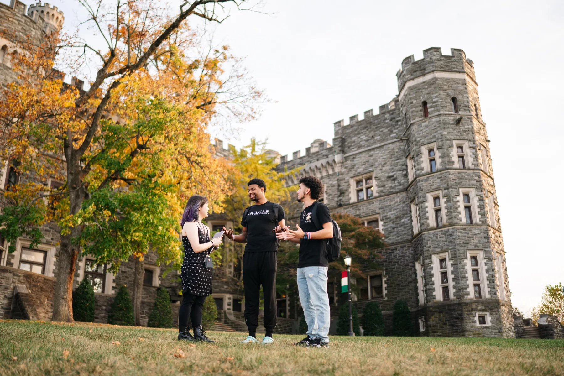 Three students hanging out with each other near the Grey Towers Castle