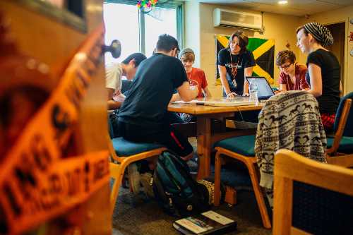 Students smiling and working at a table with laptops at the commuter lounge