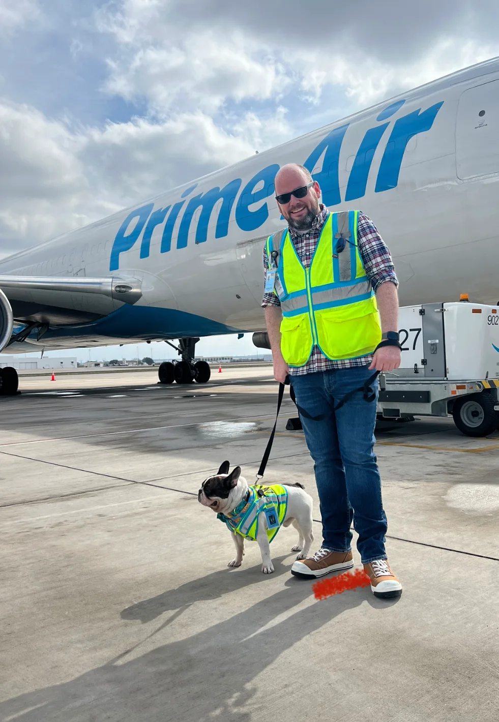 Kevin Hughes '07 standing in front of a Prime Air airplane with his dog.