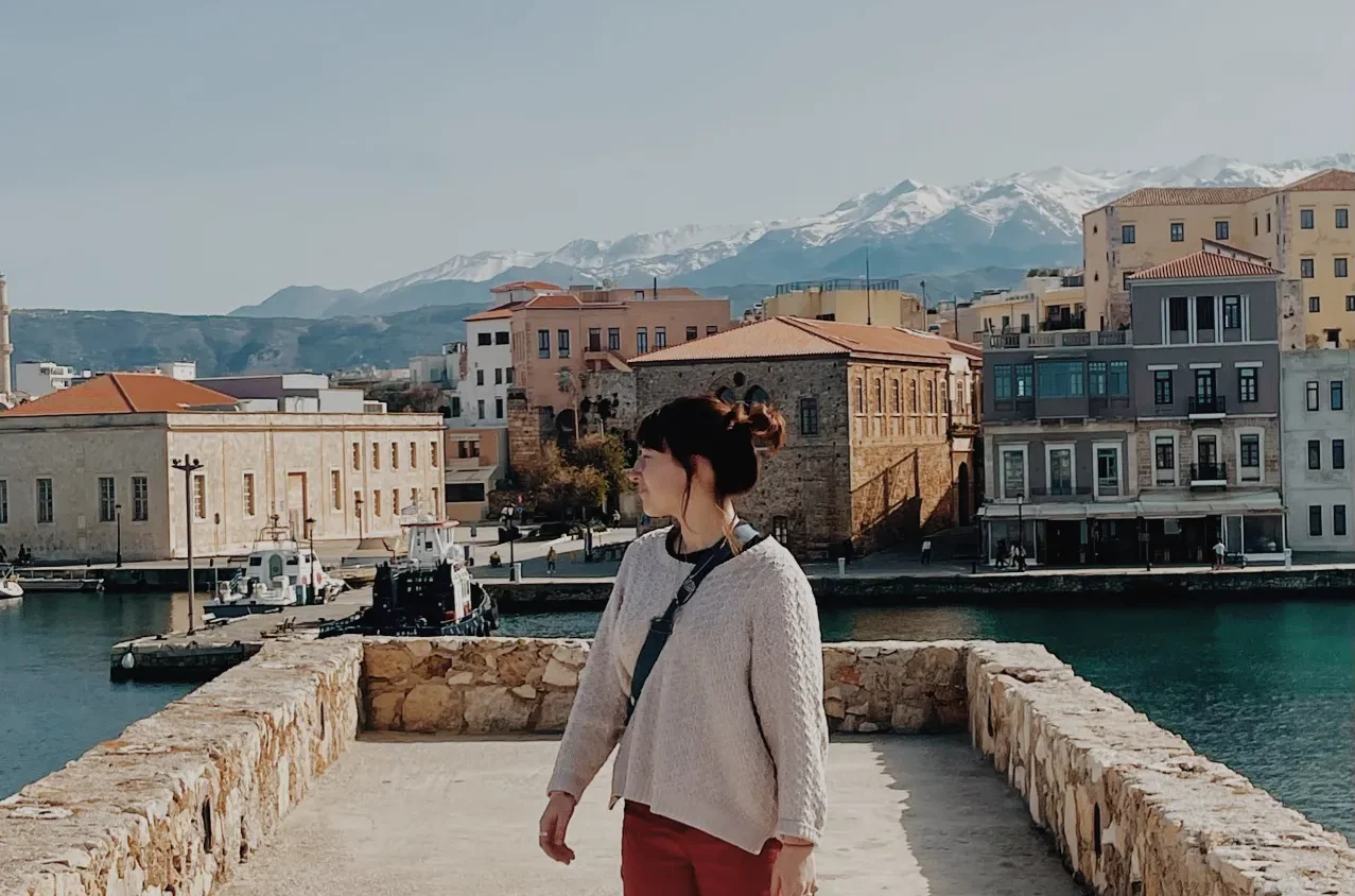 Student looking away from camera in cute Greek town with water and mountains in background