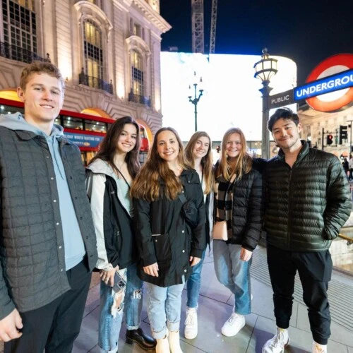 Arcadia students in smile for a picture in London in front of subway station