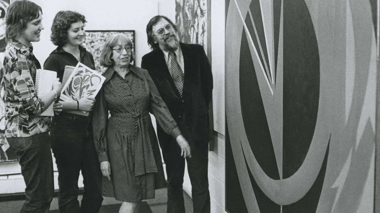 Four people viewing a large piece of artwork on the wall during an exhibition.