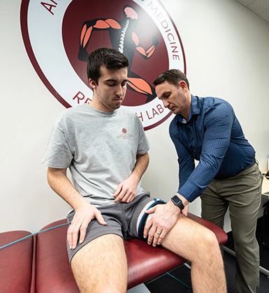 A physical therapist helps a patient with a leg injury during an exam.