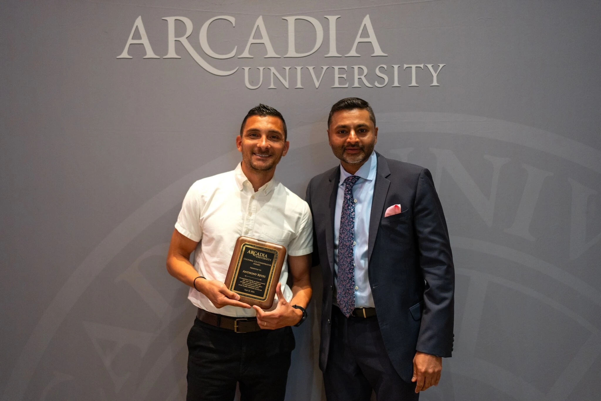 Anthony Reyes holds the Cultural Co-Conspirator Award and stands next to President Ajay Nair