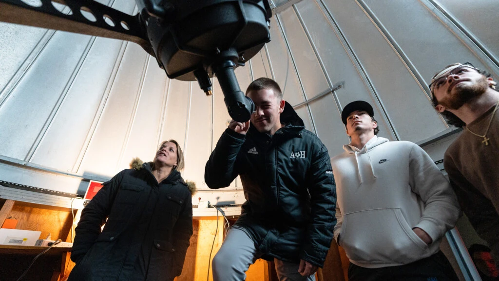 Four students work with a telescope in the Observatory at Boyer Hall of Science.