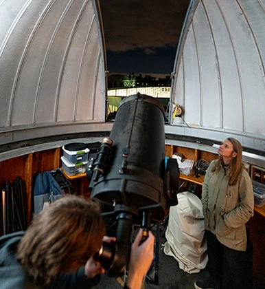 Students work inside the Observatory at Boyer Hall of Science under night skies.