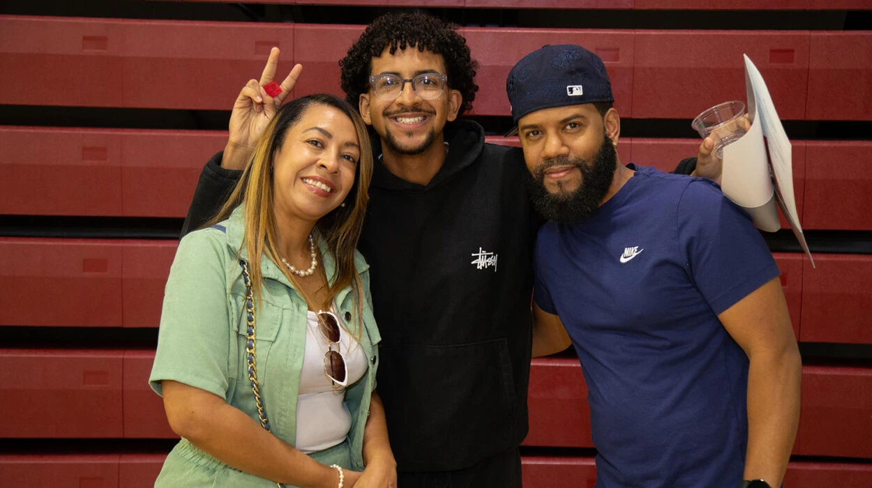 A student posing with their family while making a peace sign with their fingers