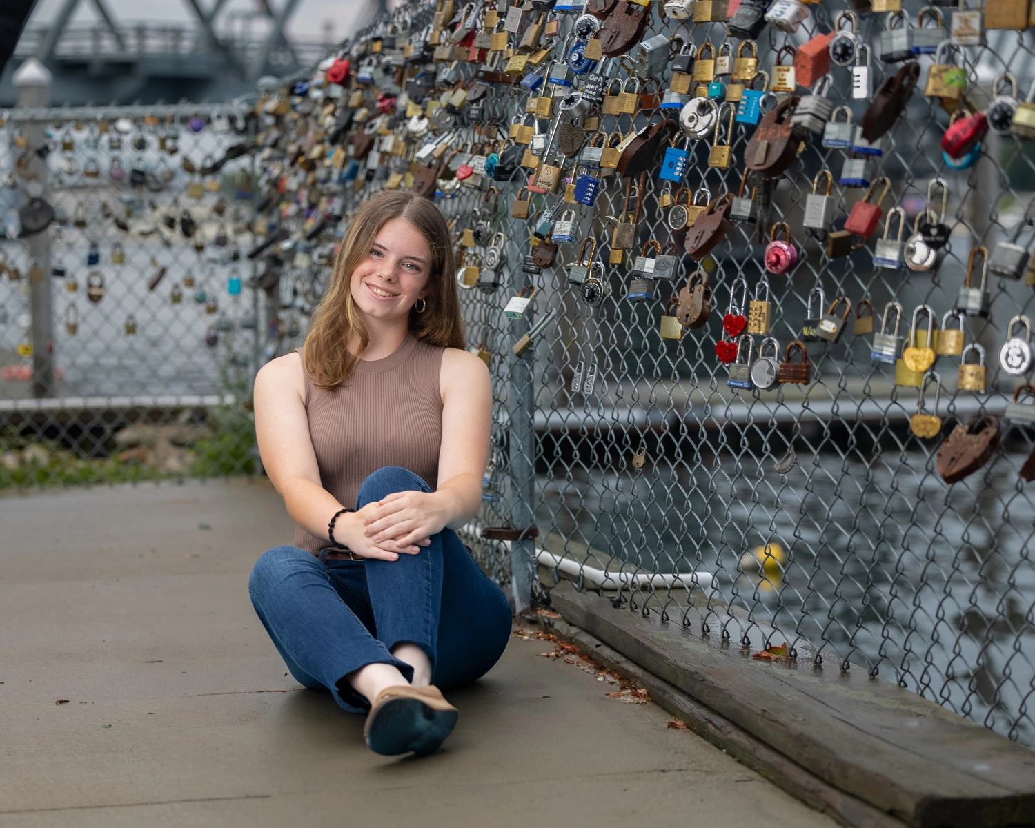 Ella Walsh sitting on the ground next to a fence with padlocks attached to it.