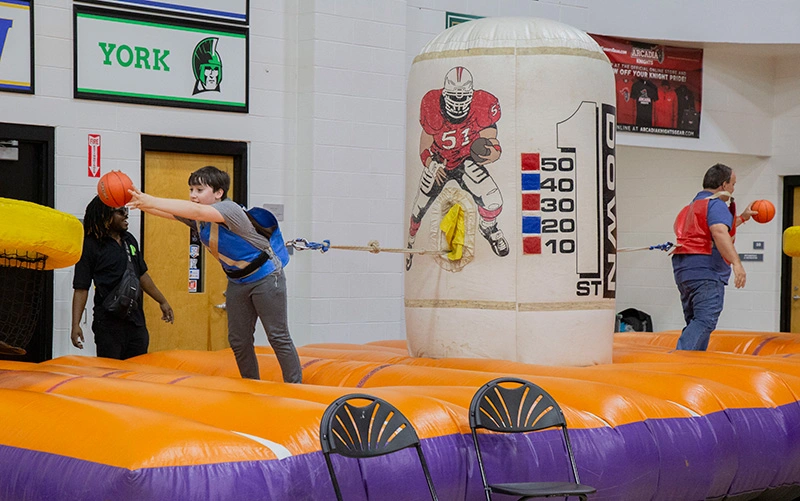 People tied to an inflatable throwing a basketball. .