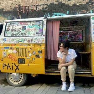 A woman sits in the open door of a van that says "Photo Bus" on the side