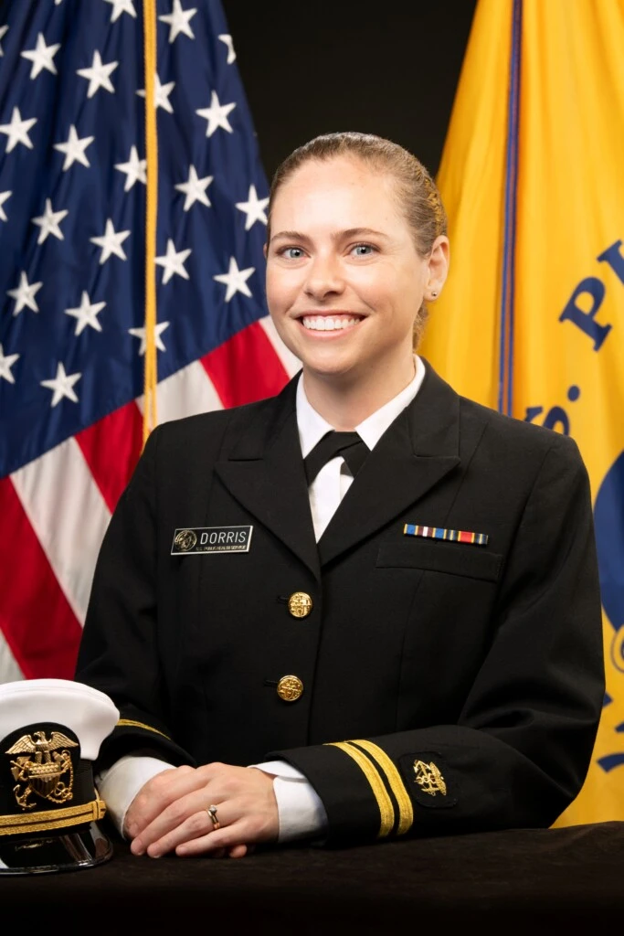 blonde woman smiling in government regalia in front of the USA flag