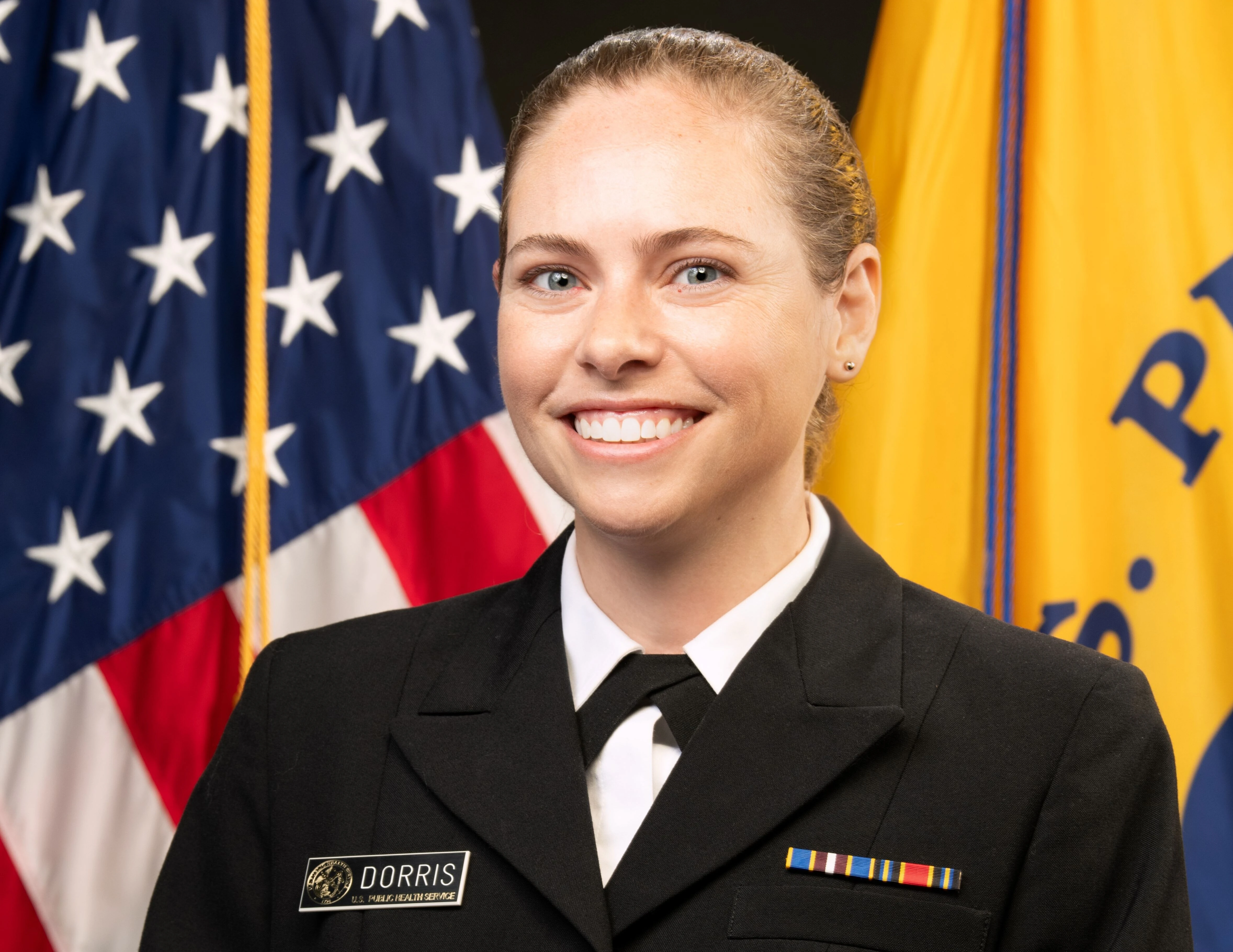 blonde woman smiling in government regalia in front of the USA flag