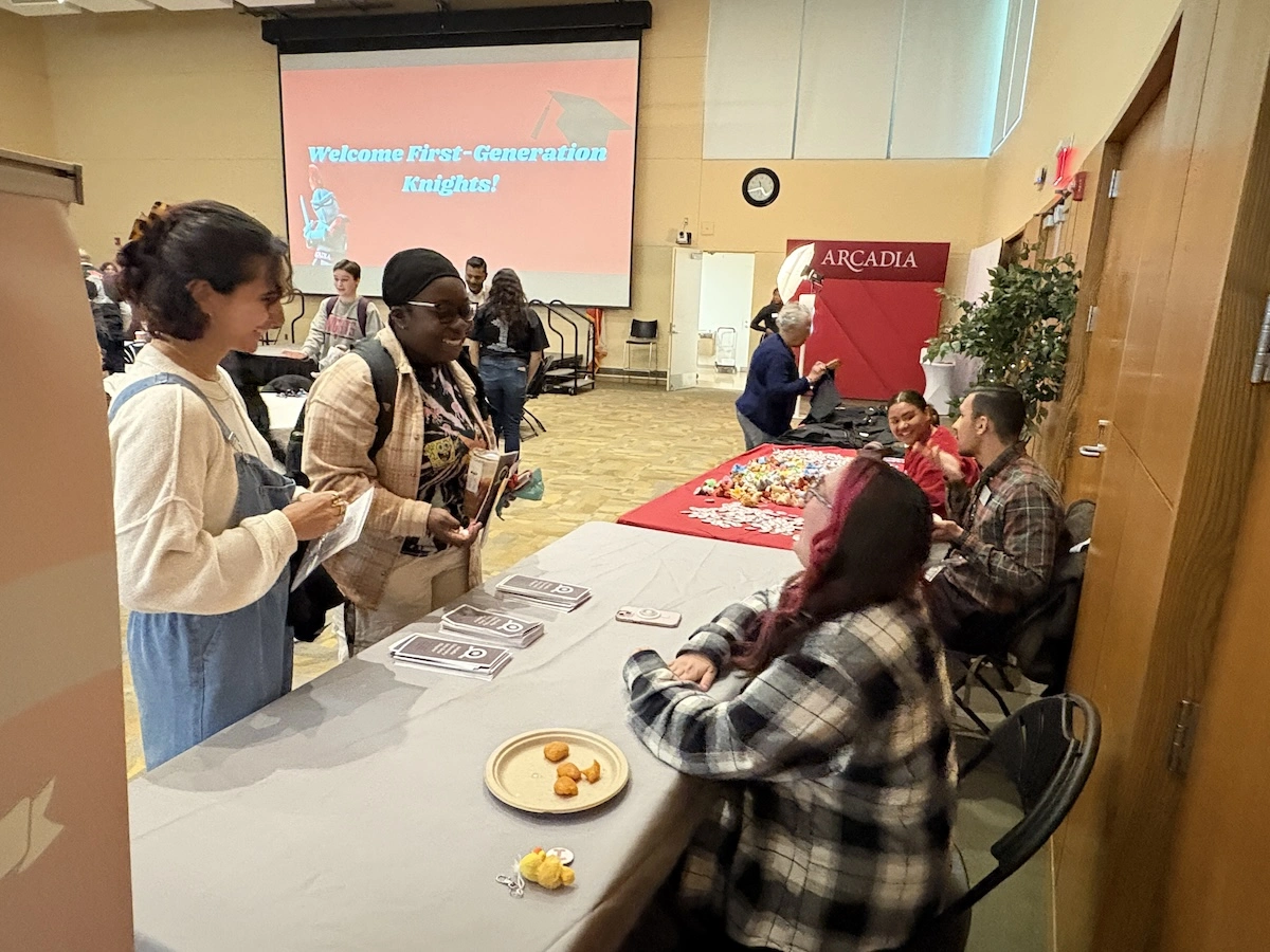 students stand at a table in the great room advertising the tri-alpha national honors society for first-gen students