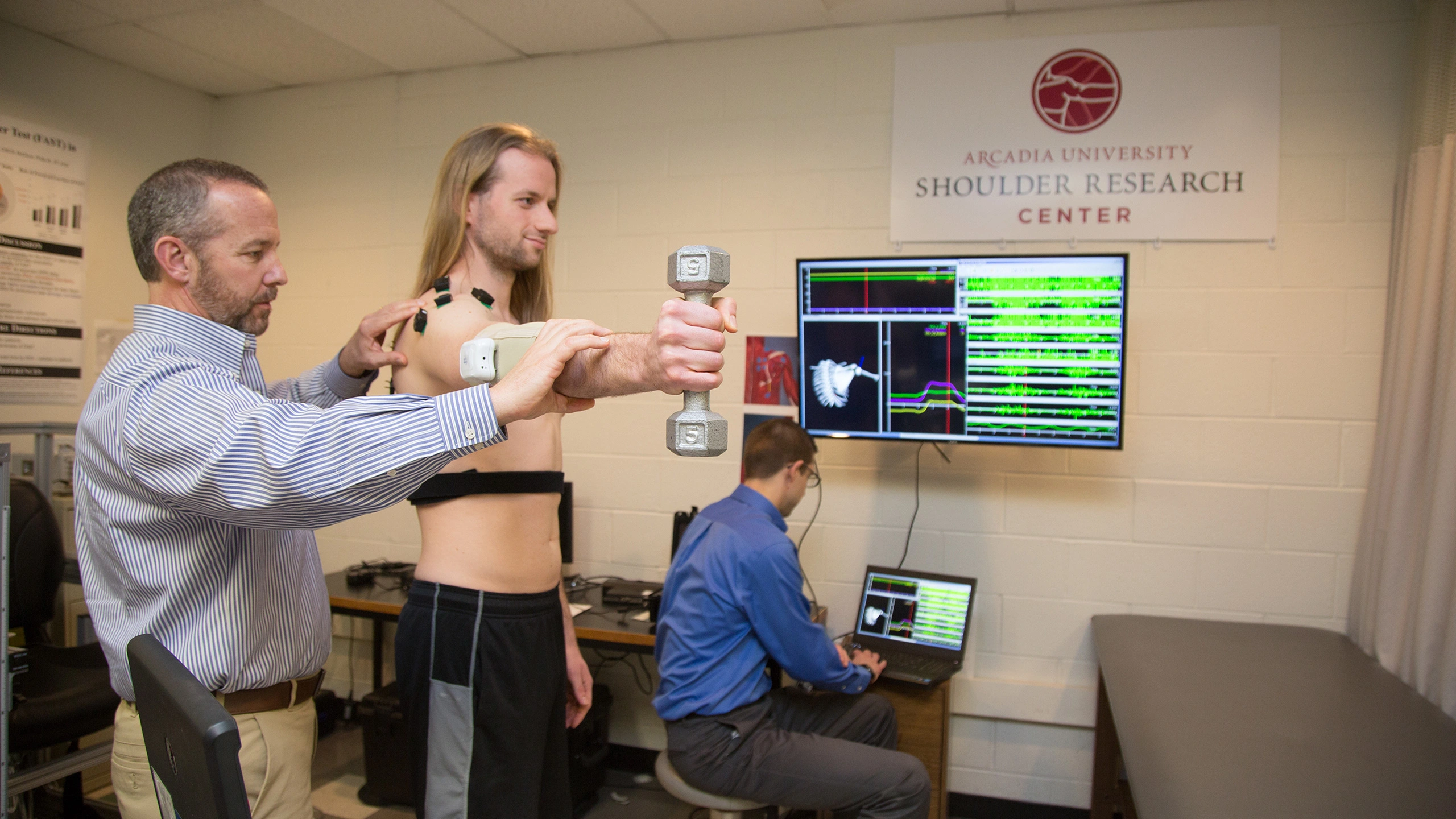 A physical therpaist works with a patient holding a weight in a simulation at the Should Research Center.