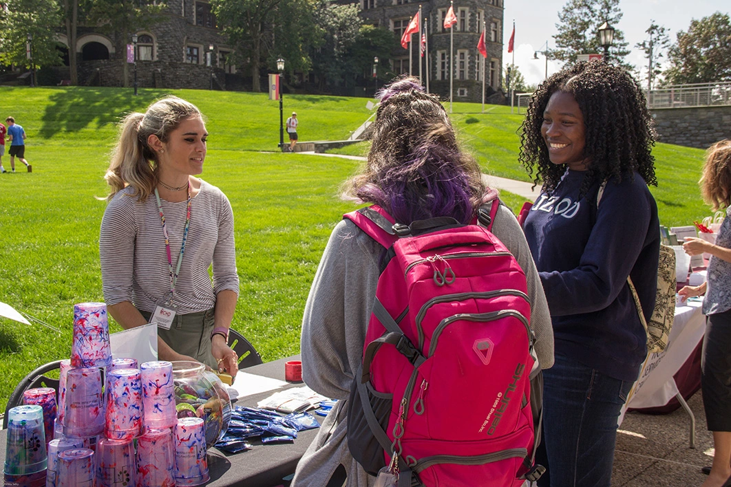 Students meet at an event table on the great lawn during a wellness fair.