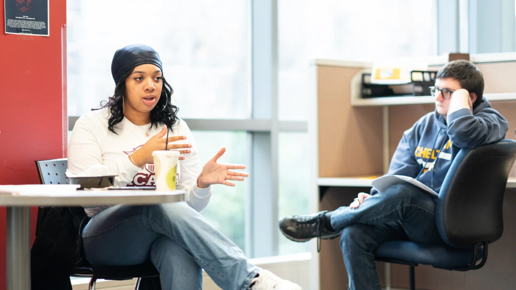 Two students talk in a lounge area about politcal science.