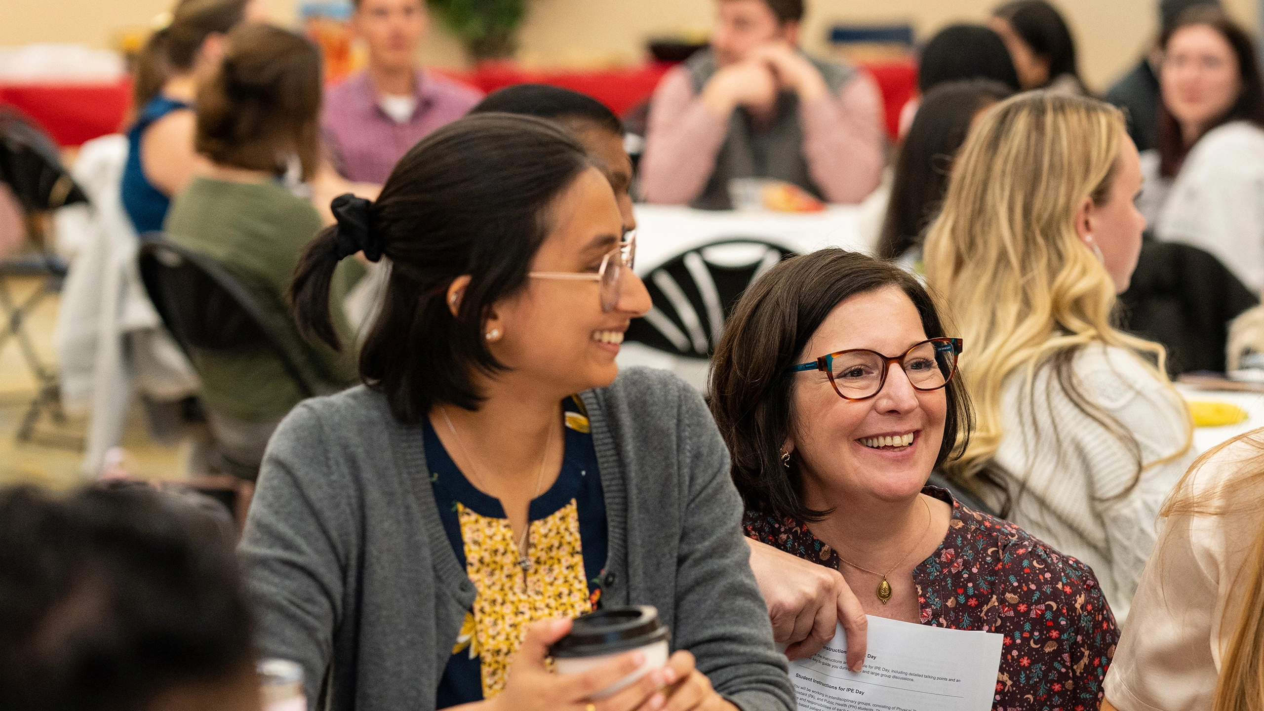 Students sit around a big round table and talk to Dené Mitchell, MPH Courses and Student Engagement Manager, during interprofessional education day '24.