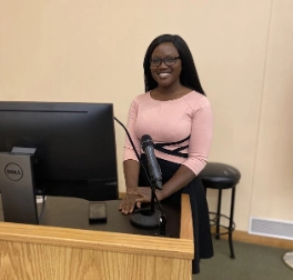 Dr. Sabrina M. Heman-Ackah,MD, DPhil (Oxon), MSE stands behind a microphone and grins during a College of Health Sciences Cross-Curricular Diversity, Equity, and Inclusion event.