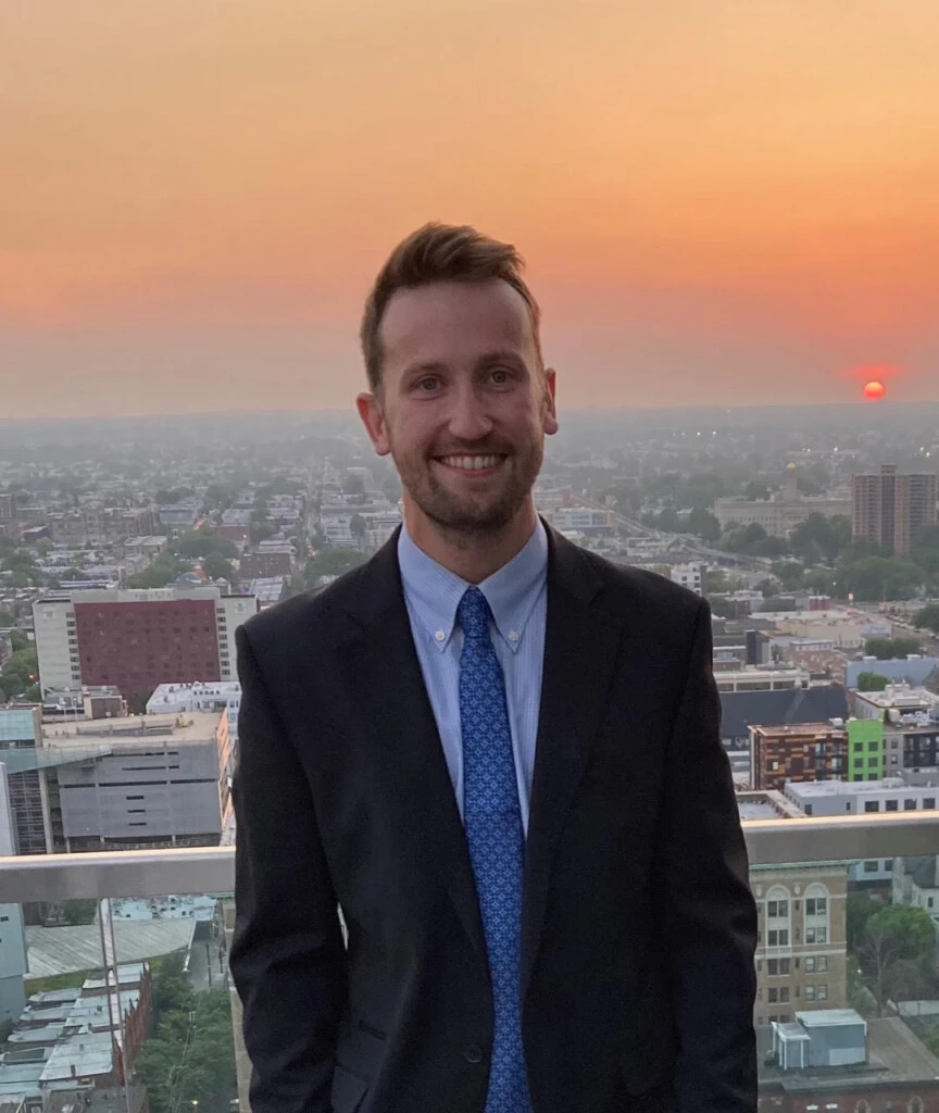 James Shaw profile image, man in suit with city at sunset behind