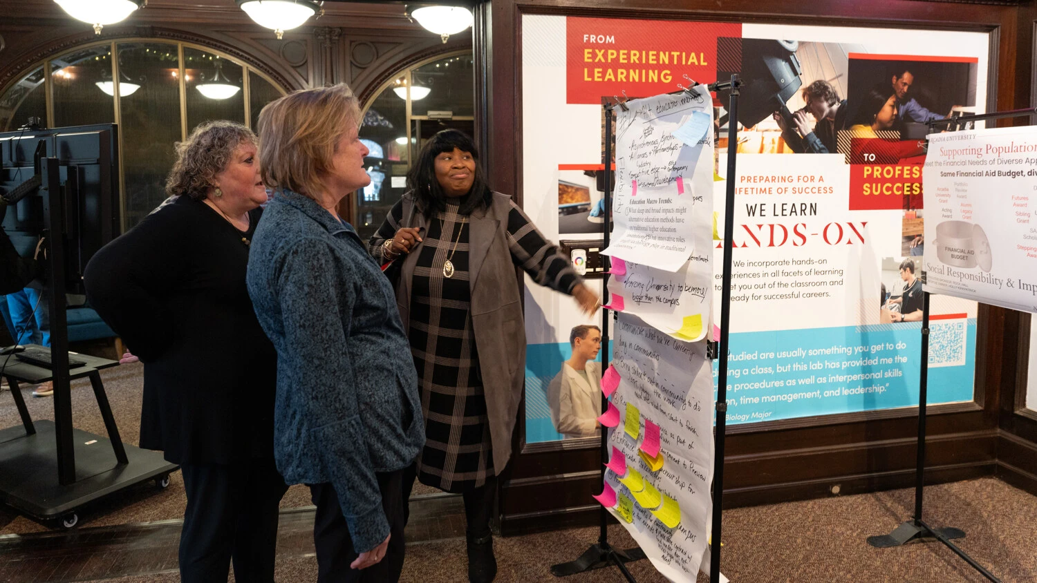 Three women talk and view displays at the Gallery Walk idea event.