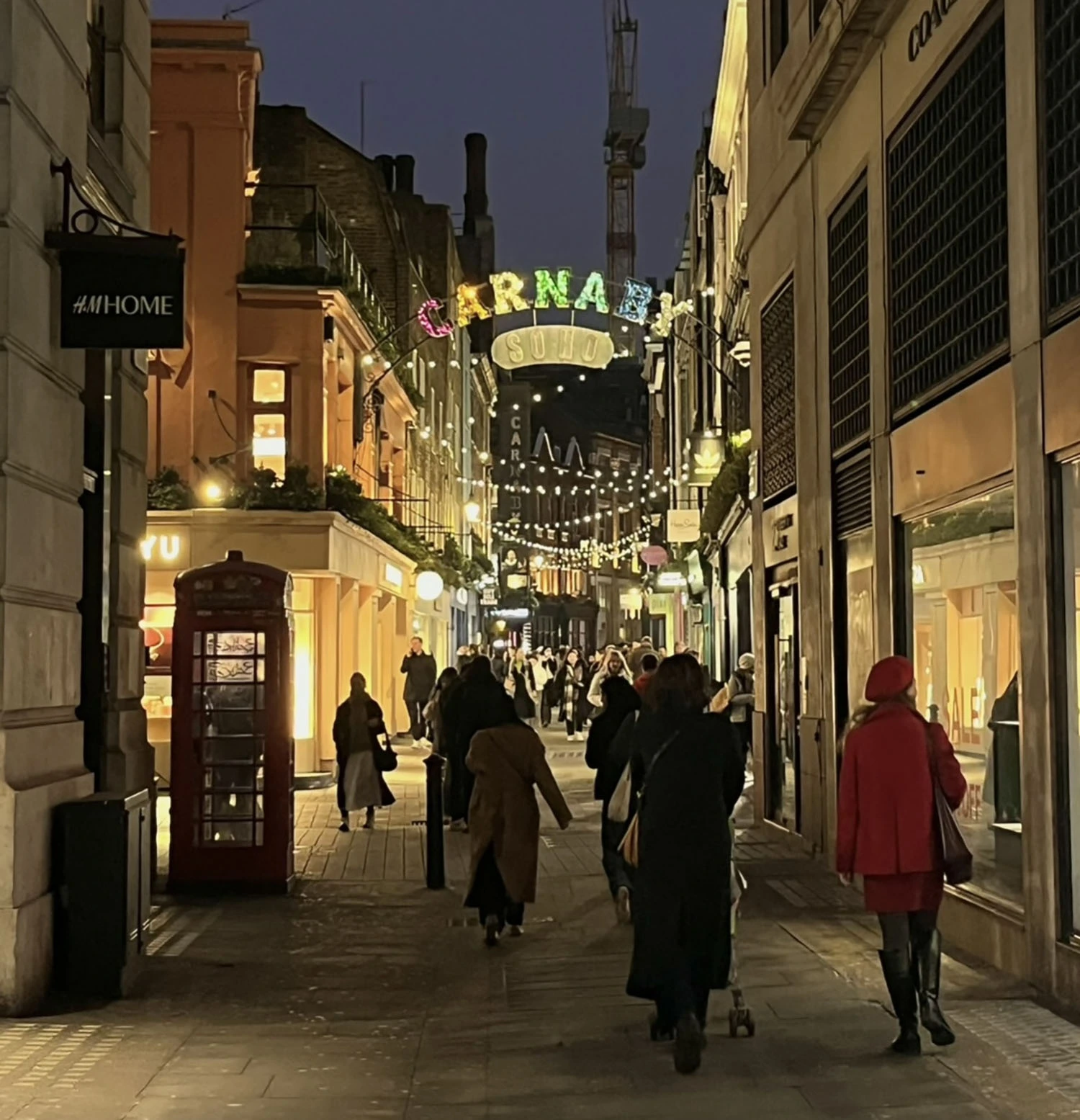 A busy street with people walking during the nighttime