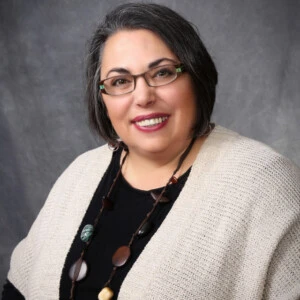 A headshot of Michele Pistone, a woman with short, dark hair and glasses